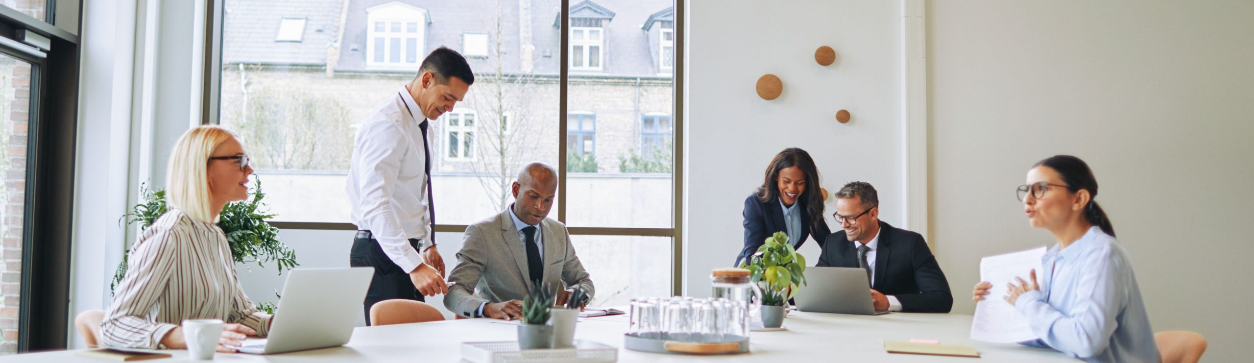 Smiling group of diverse businesspeople working together around a boardroom table in a modern office